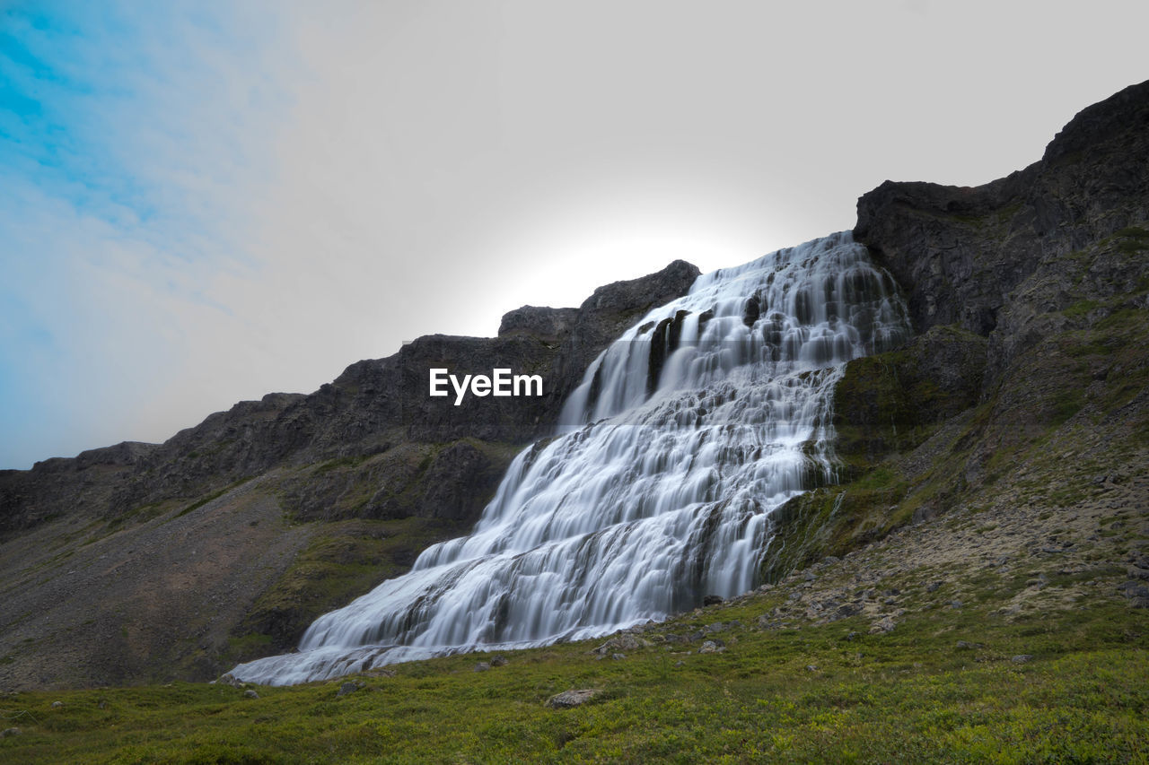 LOW ANGLE VIEW OF WATERFALL ON MOUNTAIN