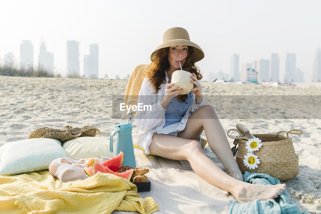 Woman drinking coconut water enjoying vacations at beach