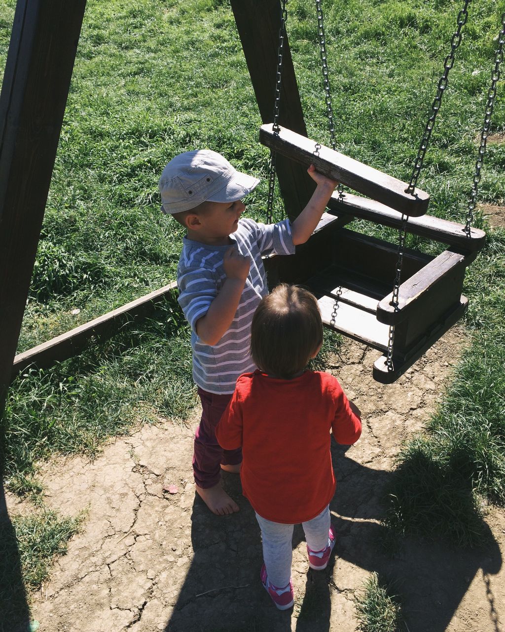 High angle view of siblings standing by swing in playground