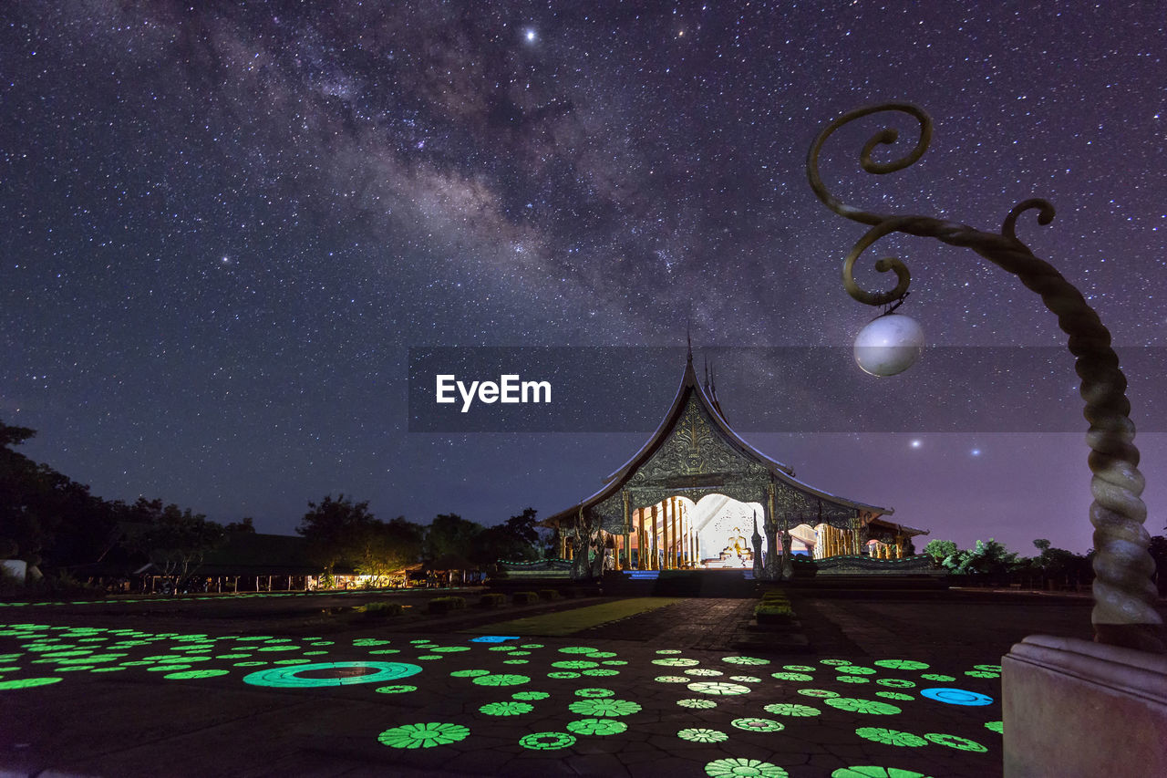 Low angle view of illuminated temple against star field at night