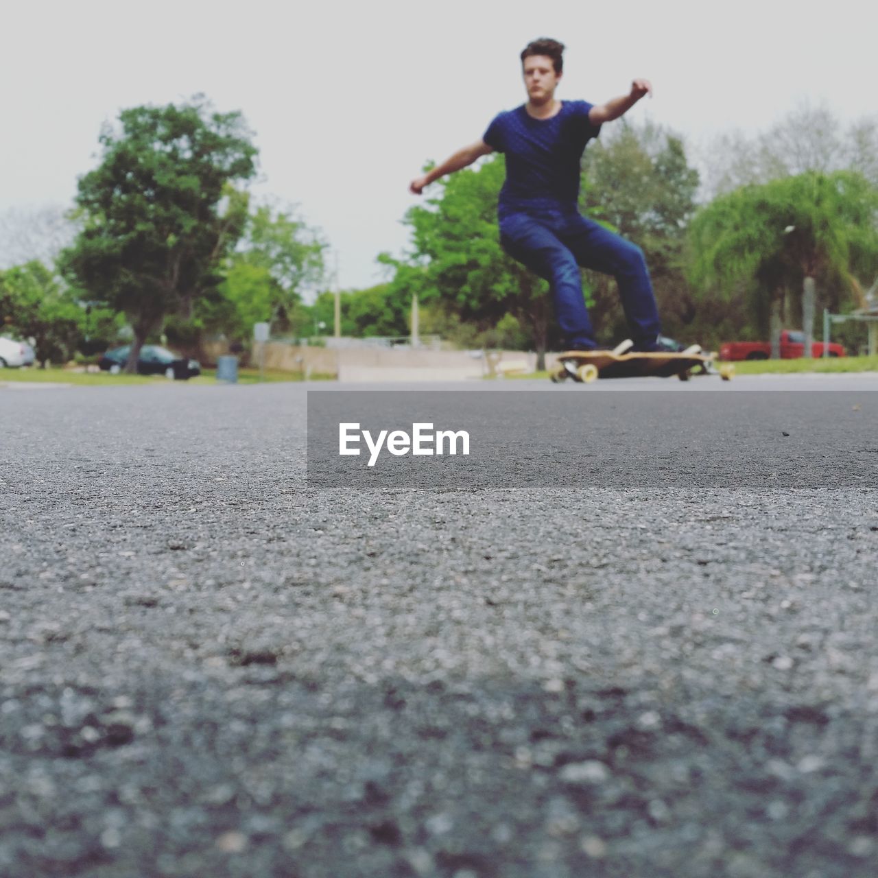 Teenage boy skateboarding on street against sky in city