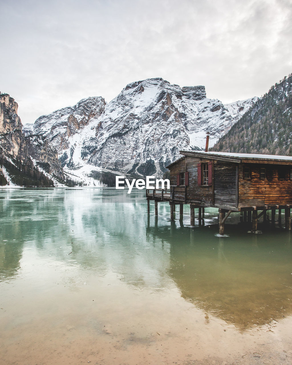 BUILT STRUCTURE BY LAKE AGAINST SKY DURING WINTER