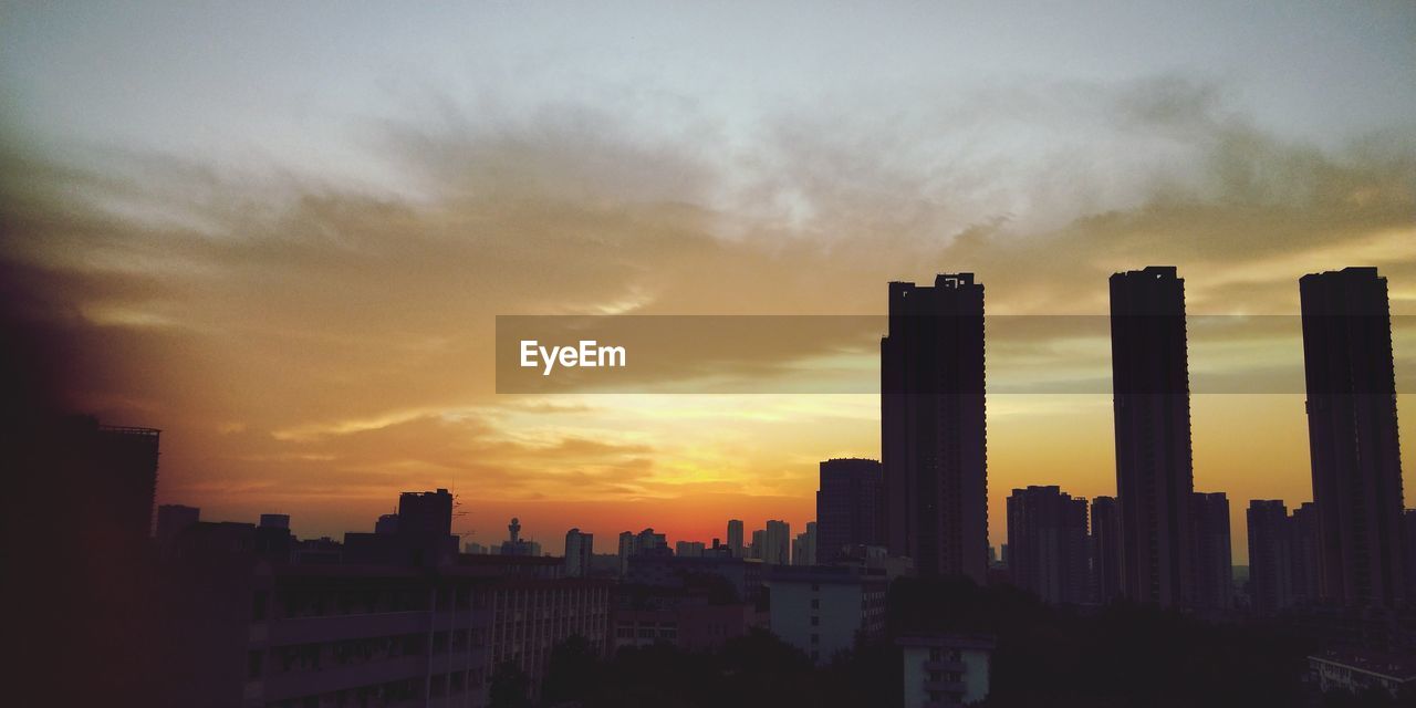 SILHOUETTE BUILDINGS AGAINST SKY AT SUNSET