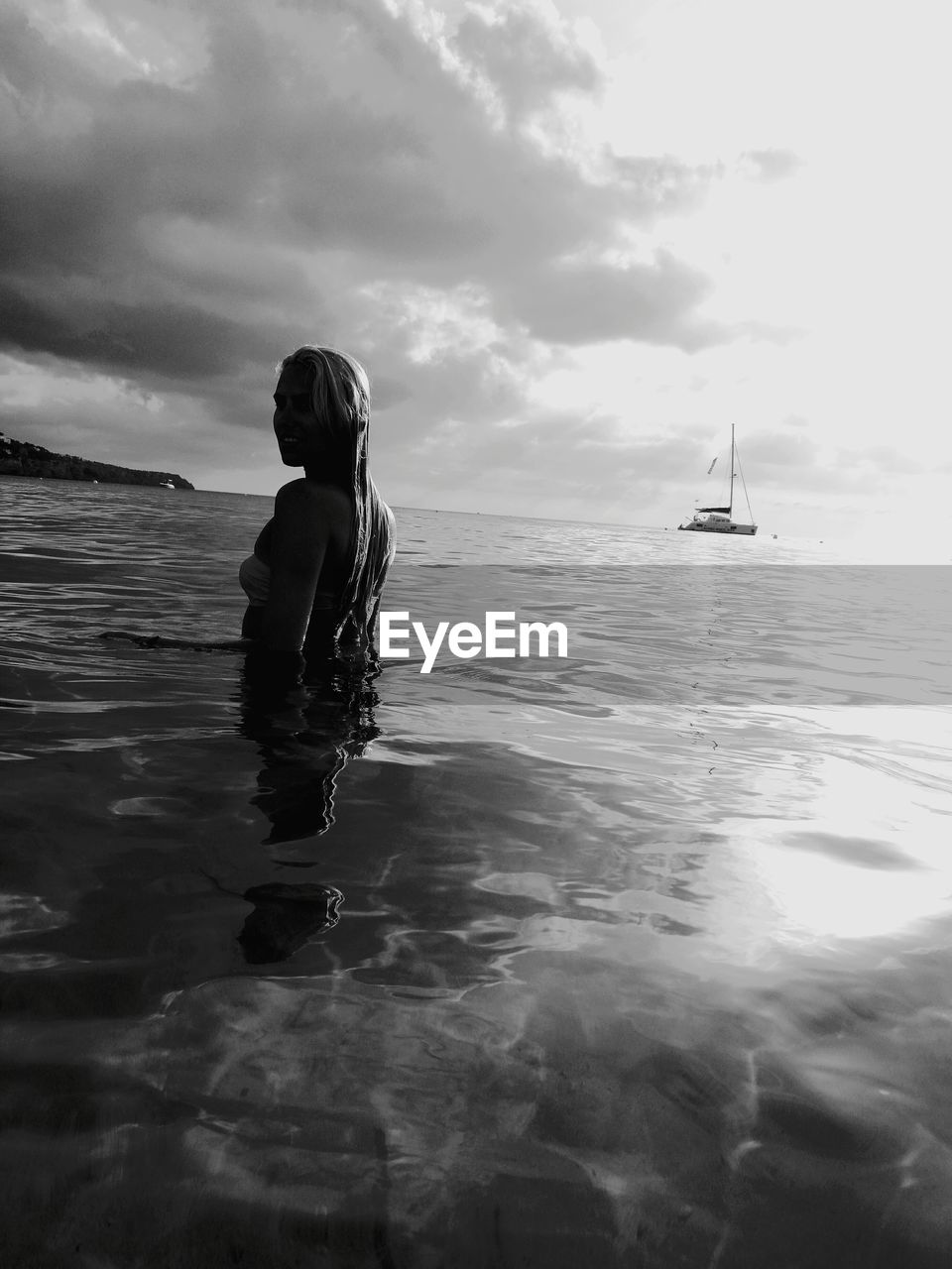 Side view of woman in sea against sky