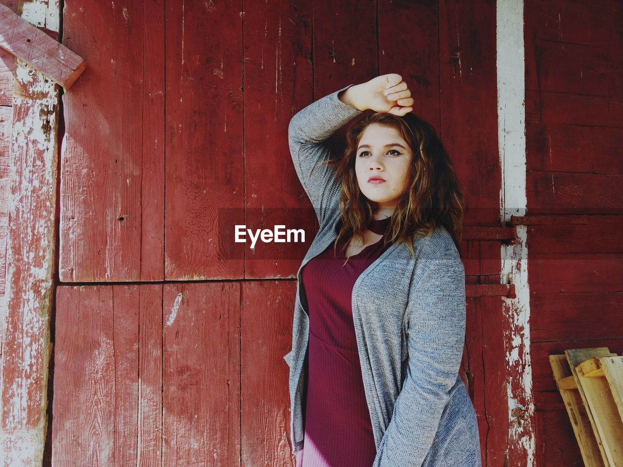 Young woman standing against wooden wall