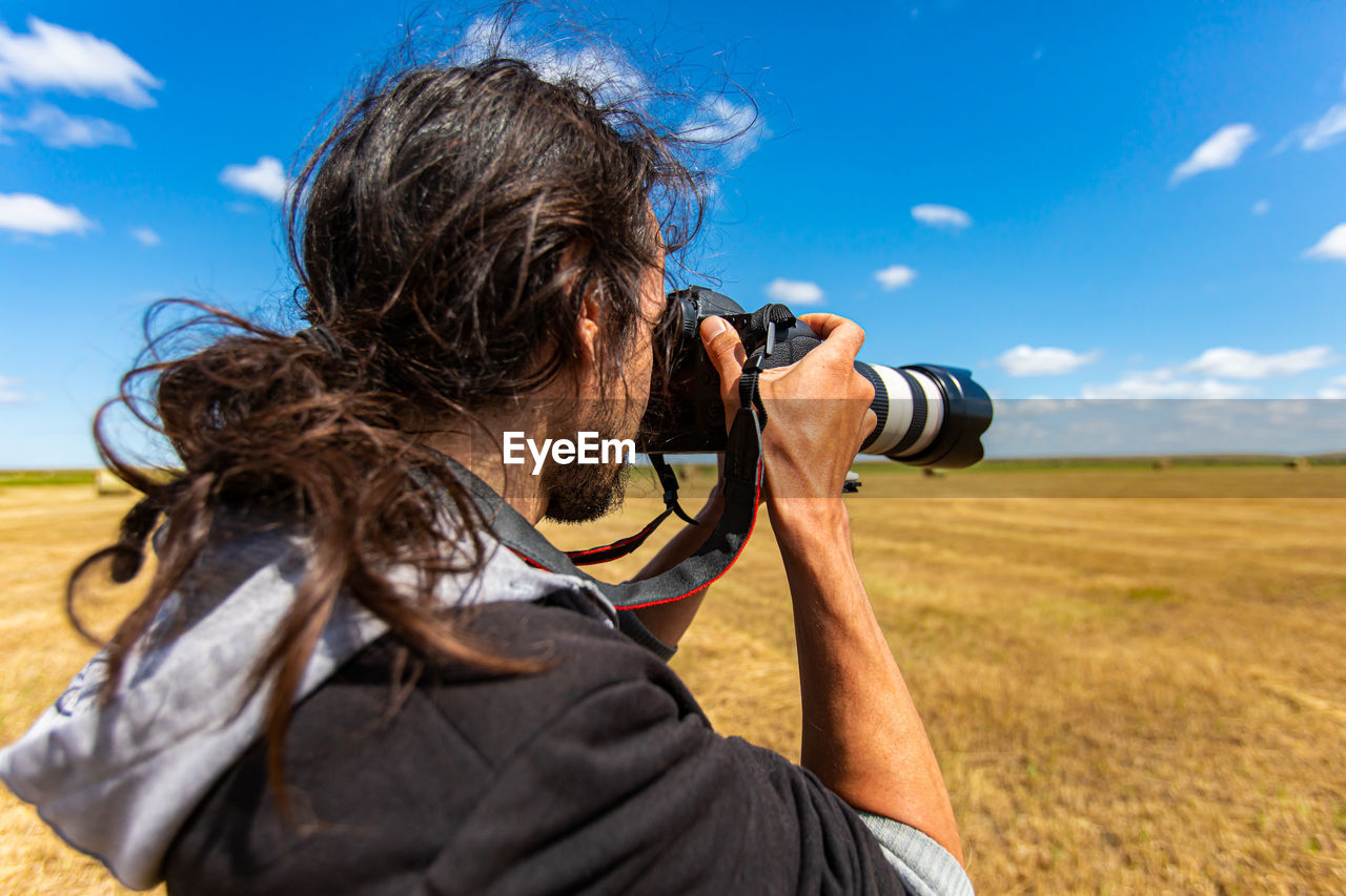 REAR VIEW OF SENIOR MAN HOLDING CAMERA