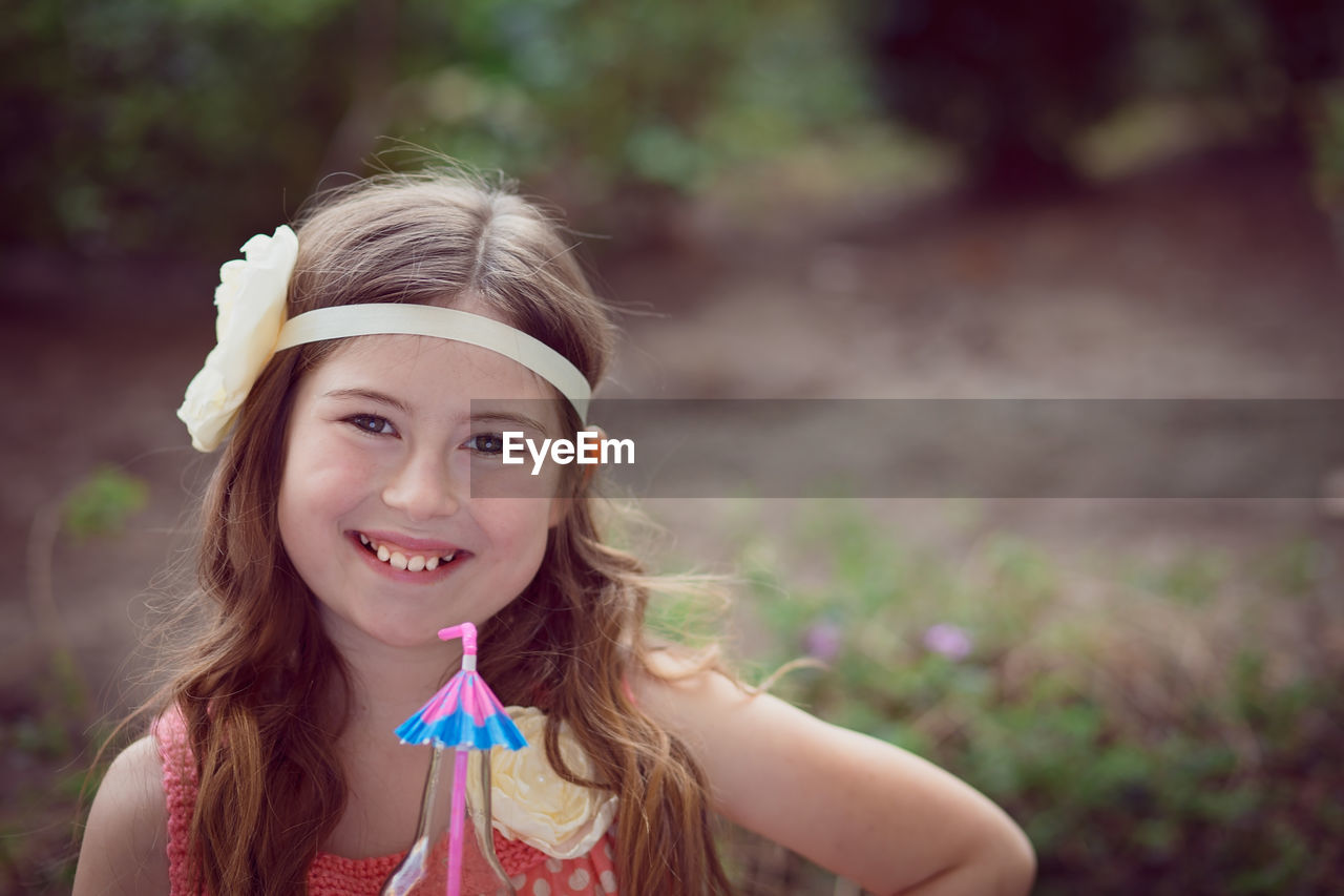 Portrait of happy girl in headband at field