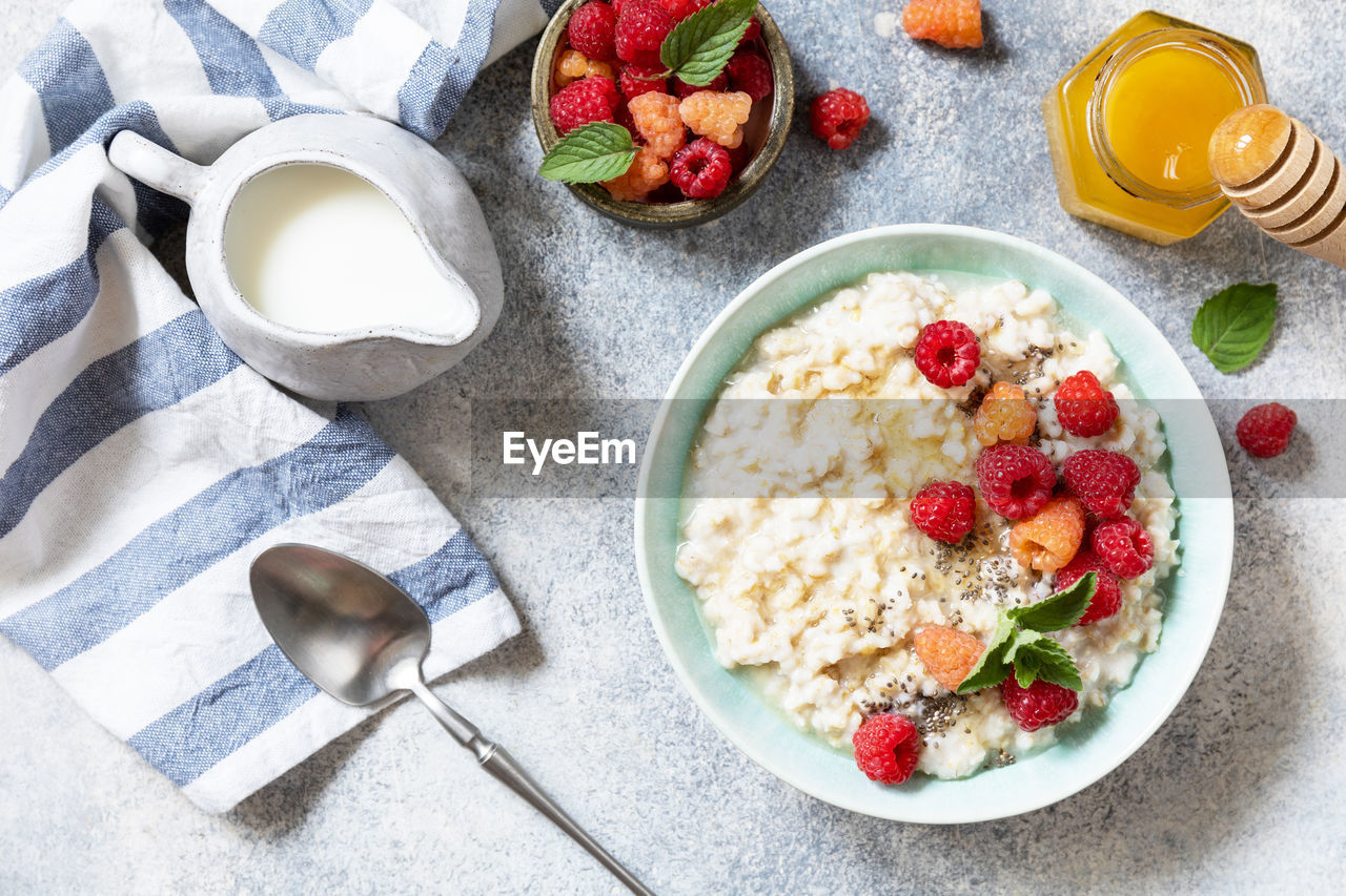 Oatmeal porridge in ceramic bowl decorated with fresh berries raspberries and chia seeds.