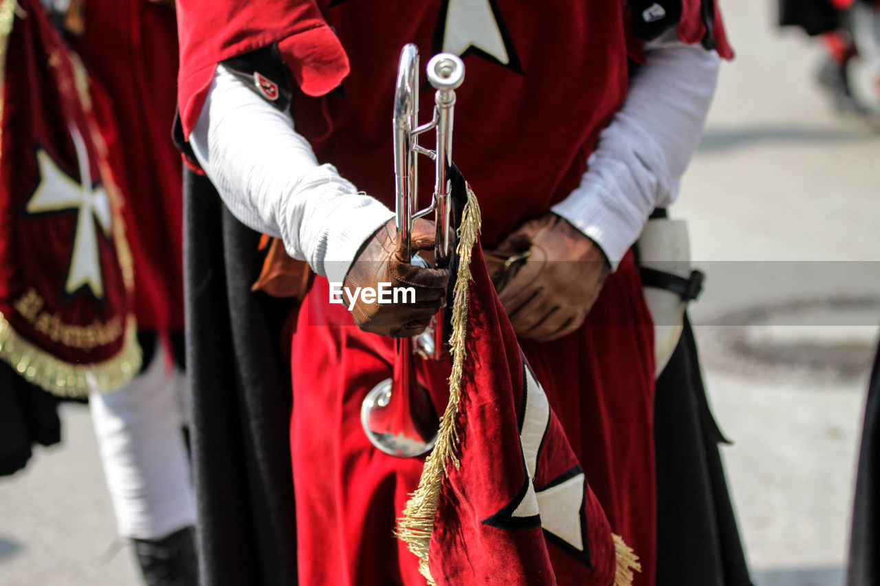 Midsection of man holding trumpet during sunny day