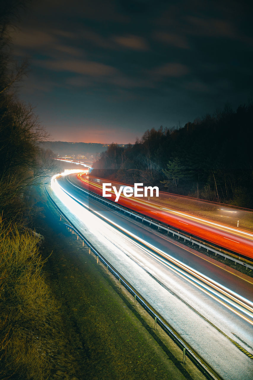 Light trails on road against sky at night