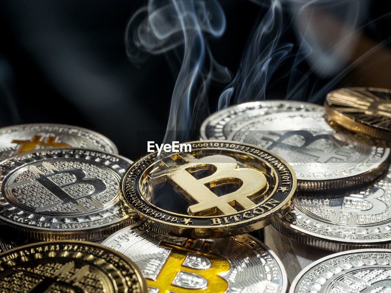 Close-up of smoke emitting from bitcoins over black background