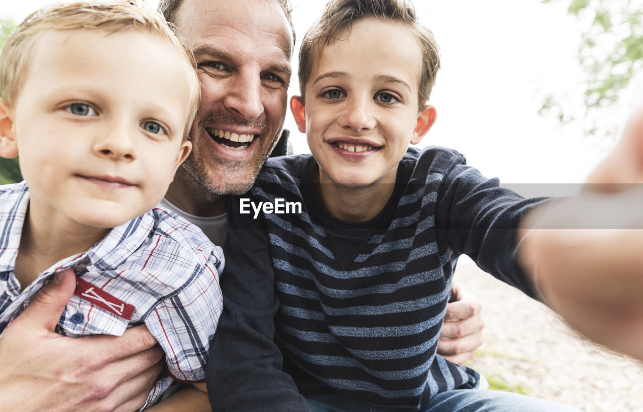 Selfie of happy father with two sons outdoors