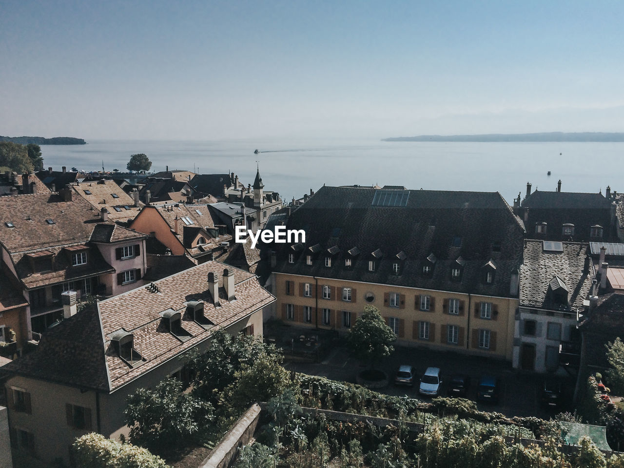 HIGH ANGLE VIEW OF CITY BY SEA AGAINST SKY