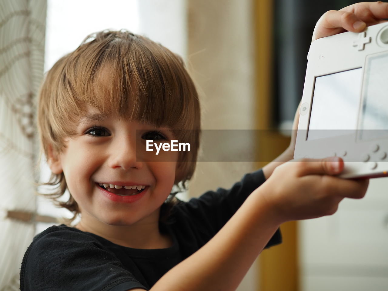 Portrait of boy holding handheld game console at home