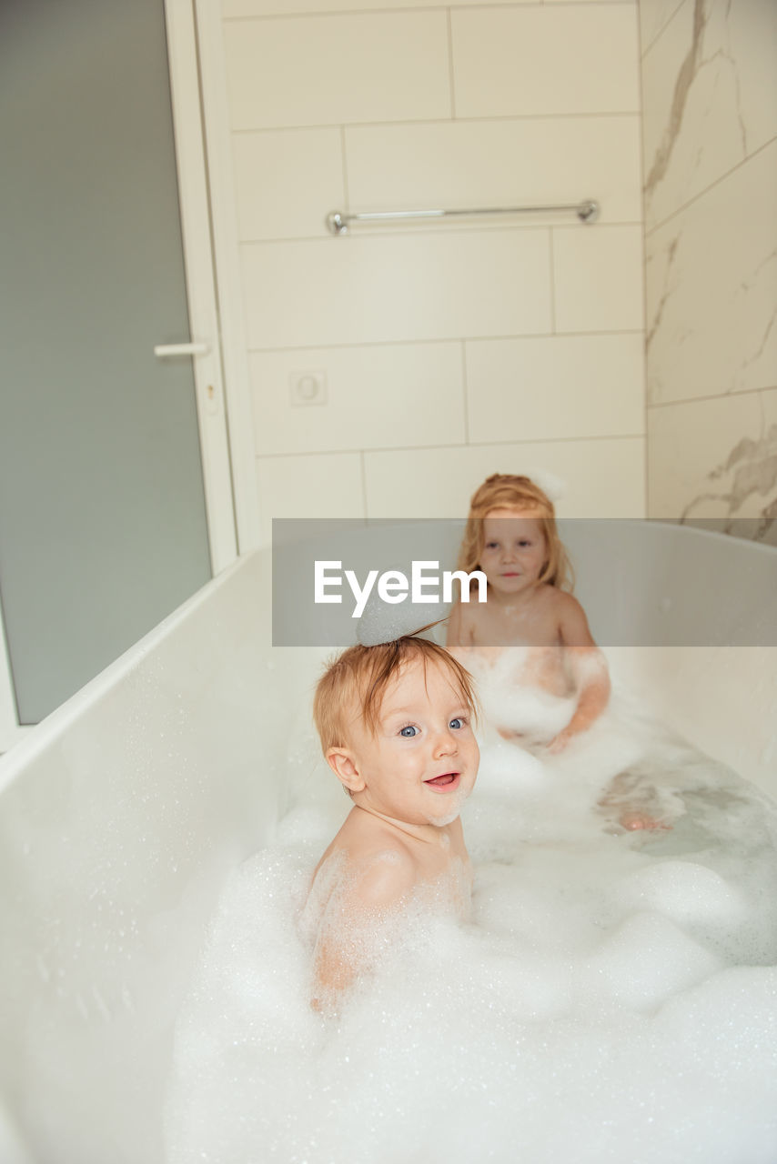 Little brother and sister bathing in a foam bath