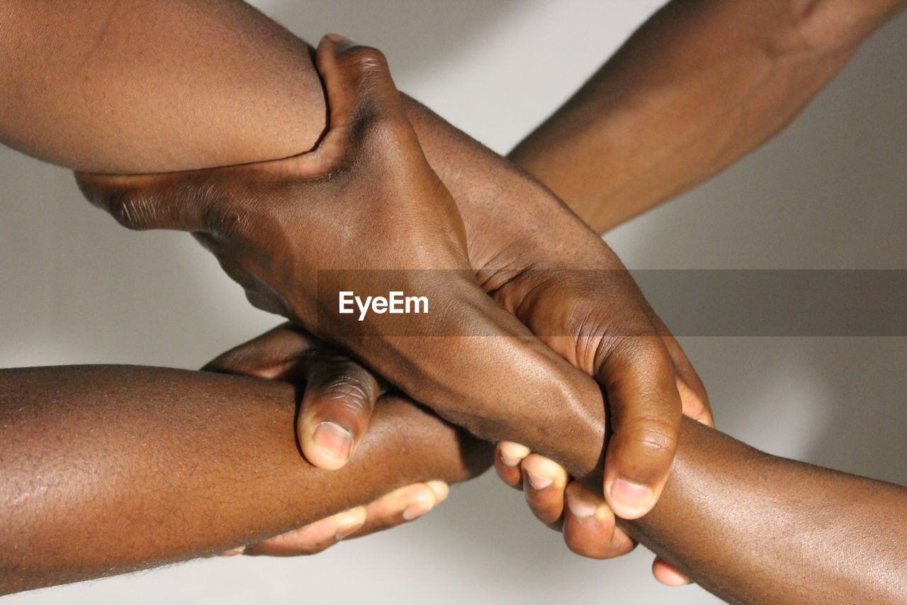 Close-up cropped friends holding hands against white background