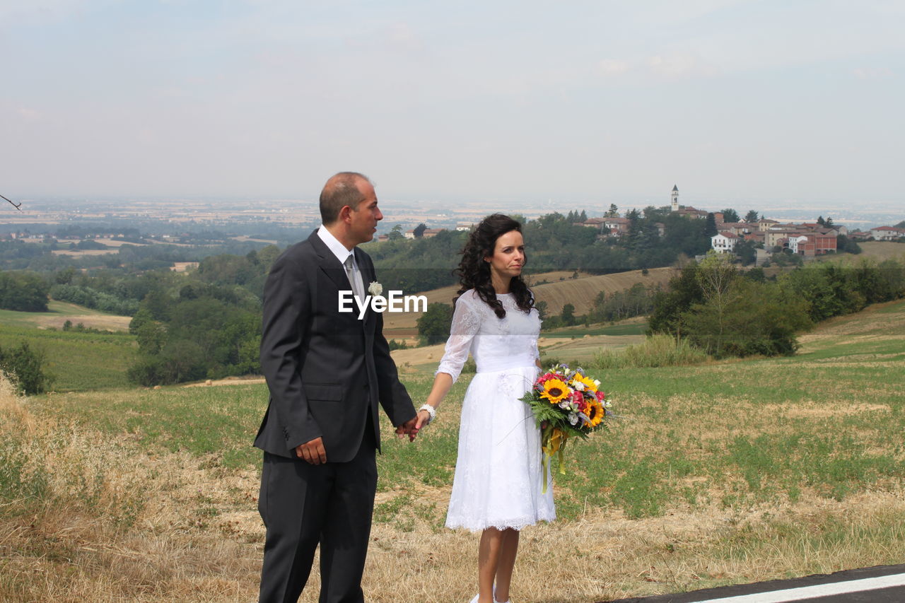 Couple standing on field against clear sky