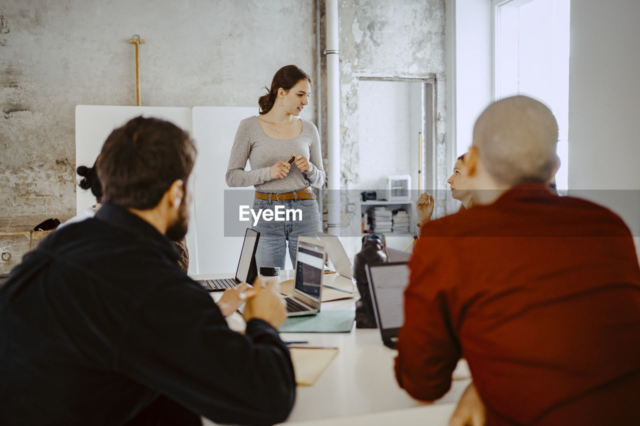 Female entrepreneur discussing with colleagues in startup company