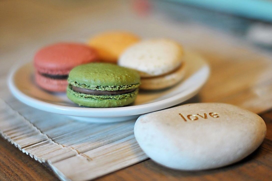 Close-up of macaroons in plate with text on pebble