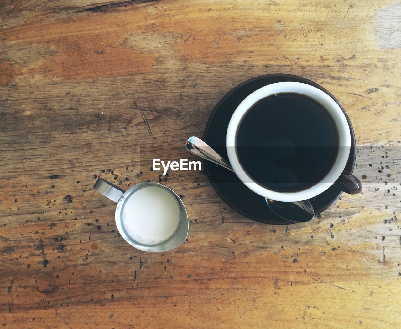 High angle view of coffee cup with milk on wooden table