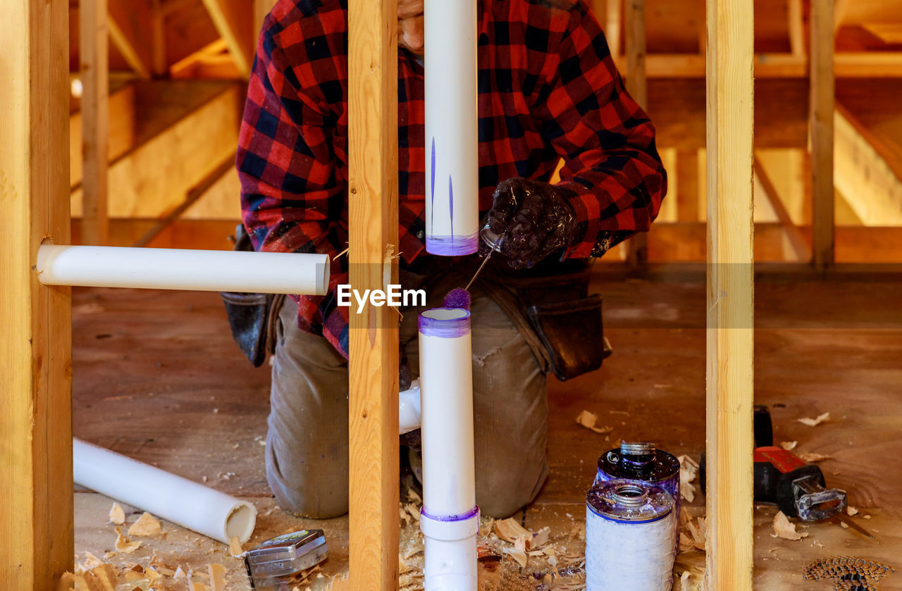 LOW SECTION OF MAN STANDING ON WOODEN FLOOR