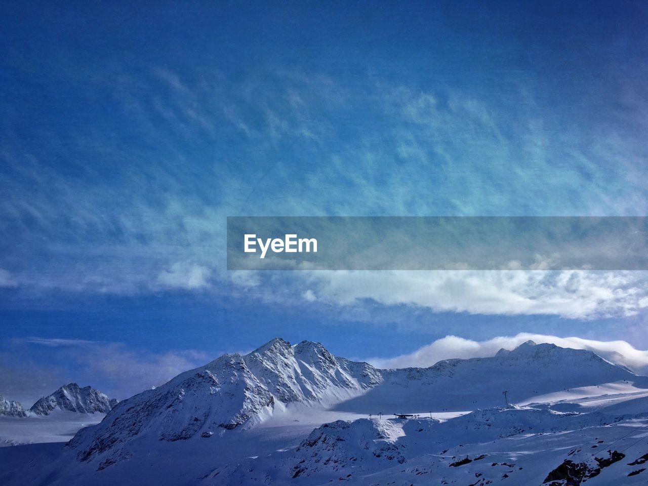 Scenic view of snowcapped mountains against cloudy blue sky