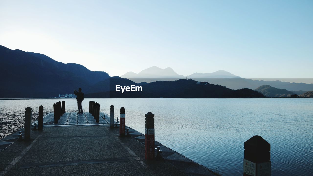 Full length of man standing on pier over river against sky