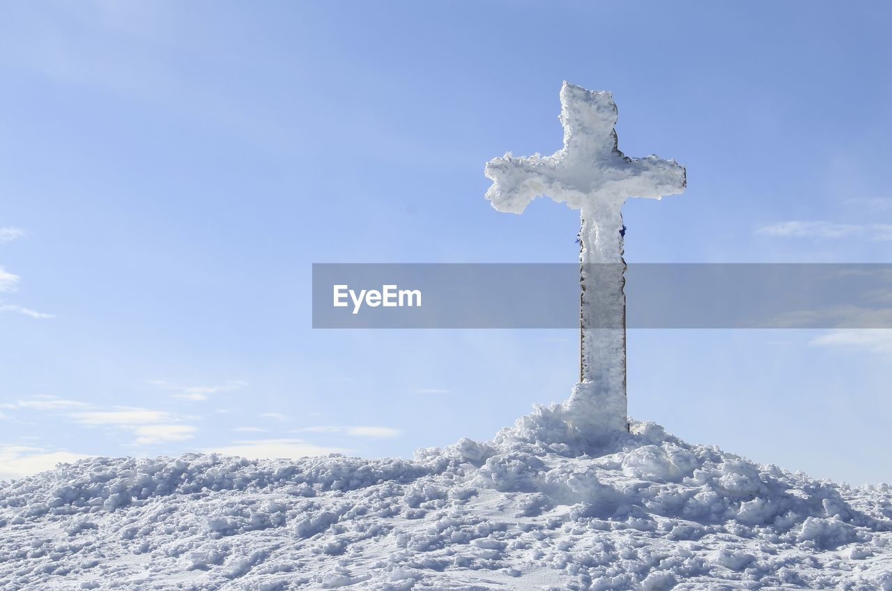 Low angle view of cross against sky during winter