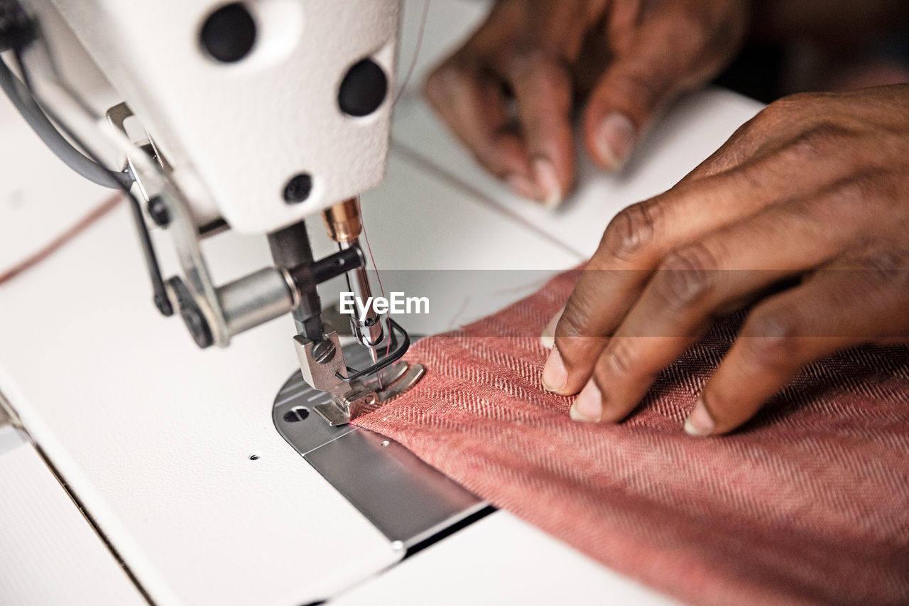 Cropped hand of tailor using sewing machine