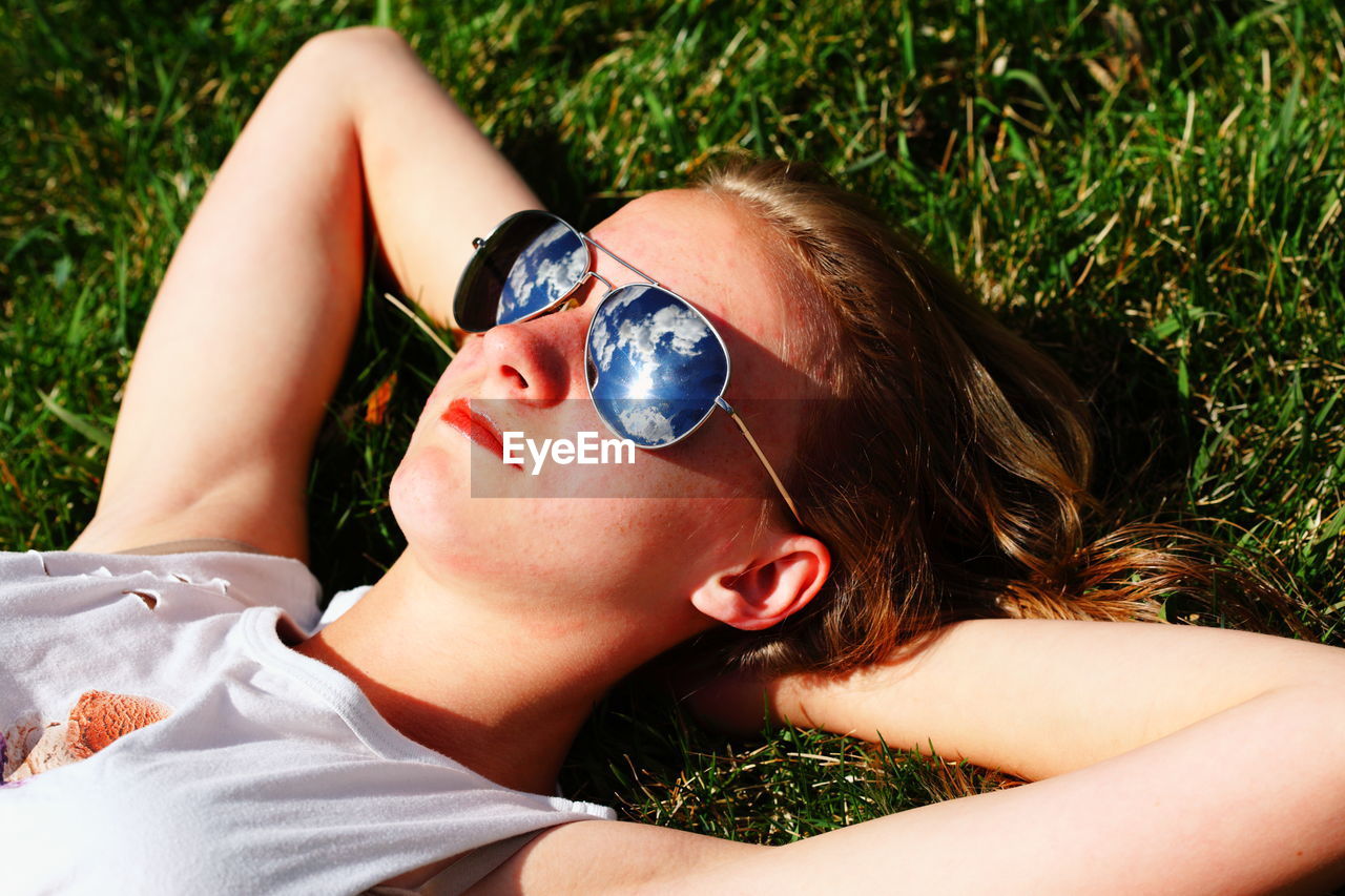 High angle view of woman in sunglass relaxing on grassy field