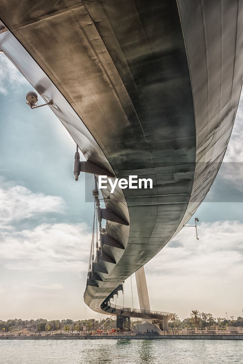 Low angle view of bridge over river against cloudy sky in city