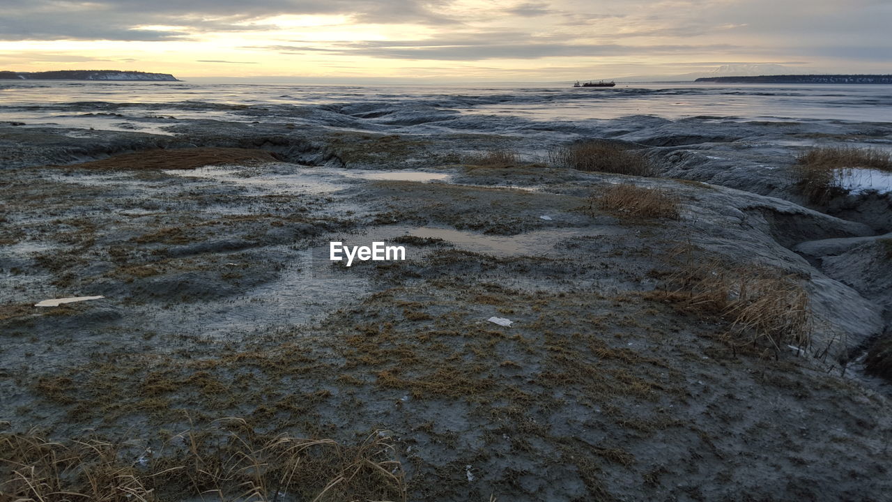 Scenic view of beach against sky during winter at sunset