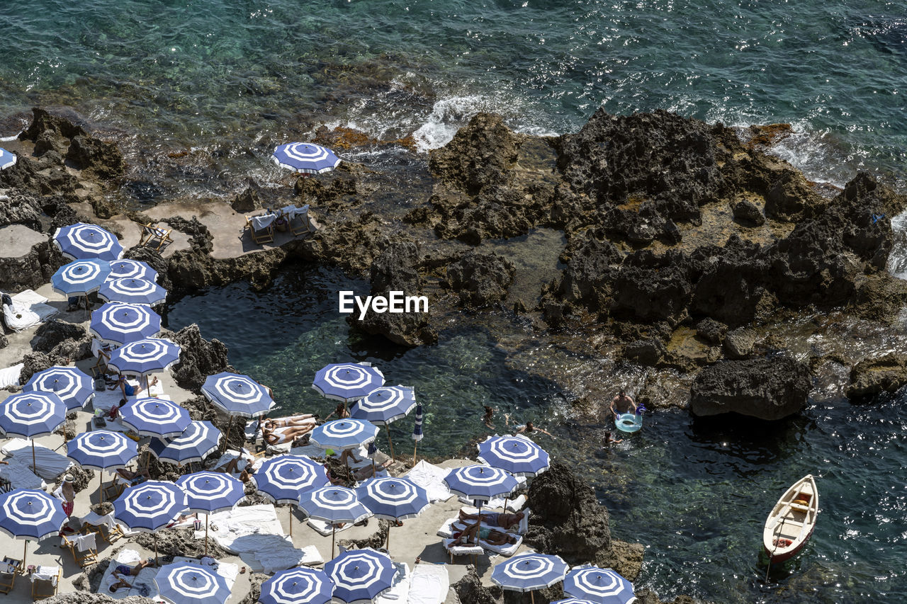 High angle view of sea, rocks and umbrellas