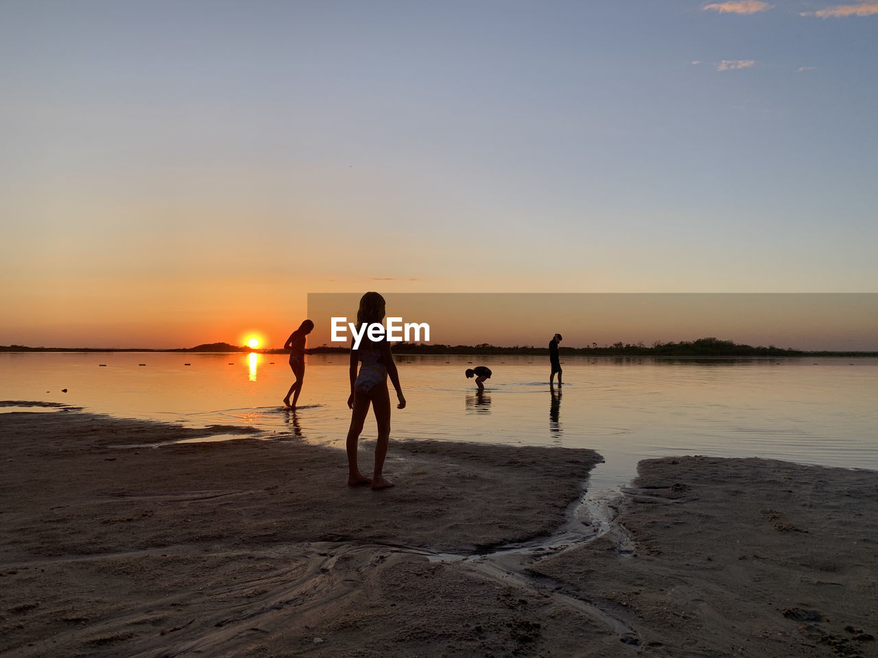 Silhouette of kids at beach at sunset