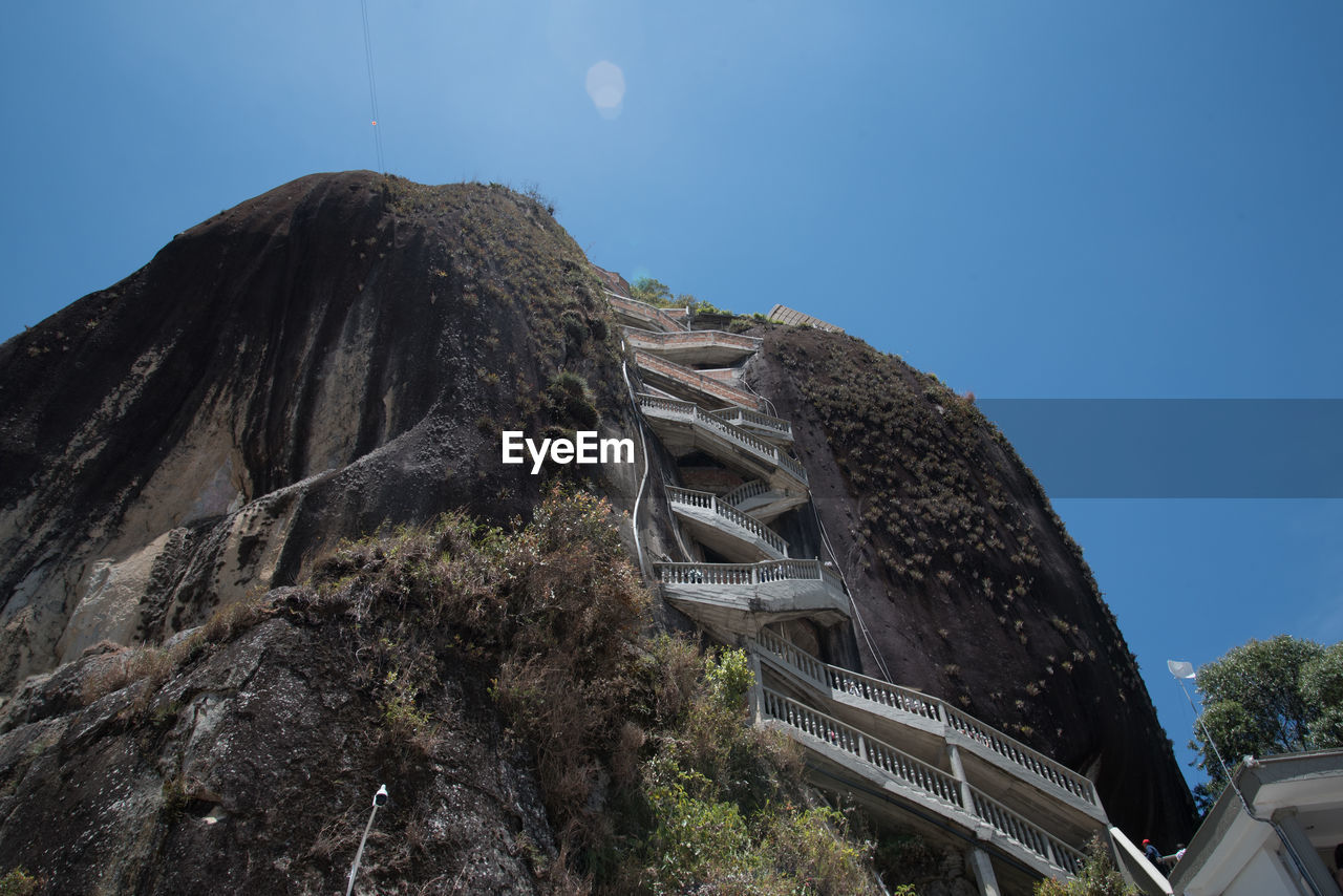 Low angle view of volcanic mountain against blue sky