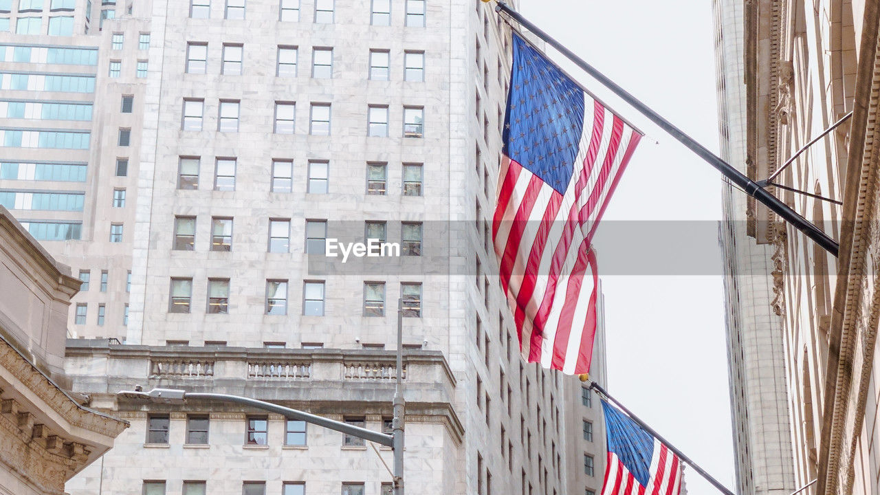 Low angle view of american flags on office buildings in new york 