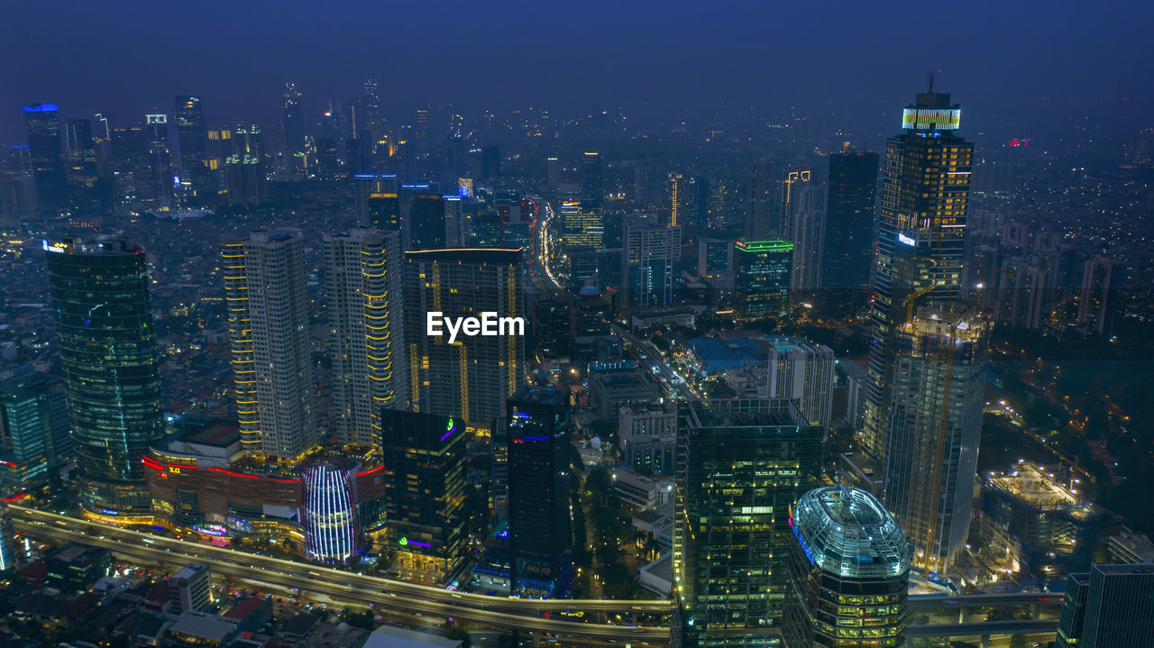 AERIAL VIEW OF ILLUMINATED CITY BUILDINGS AT NIGHT