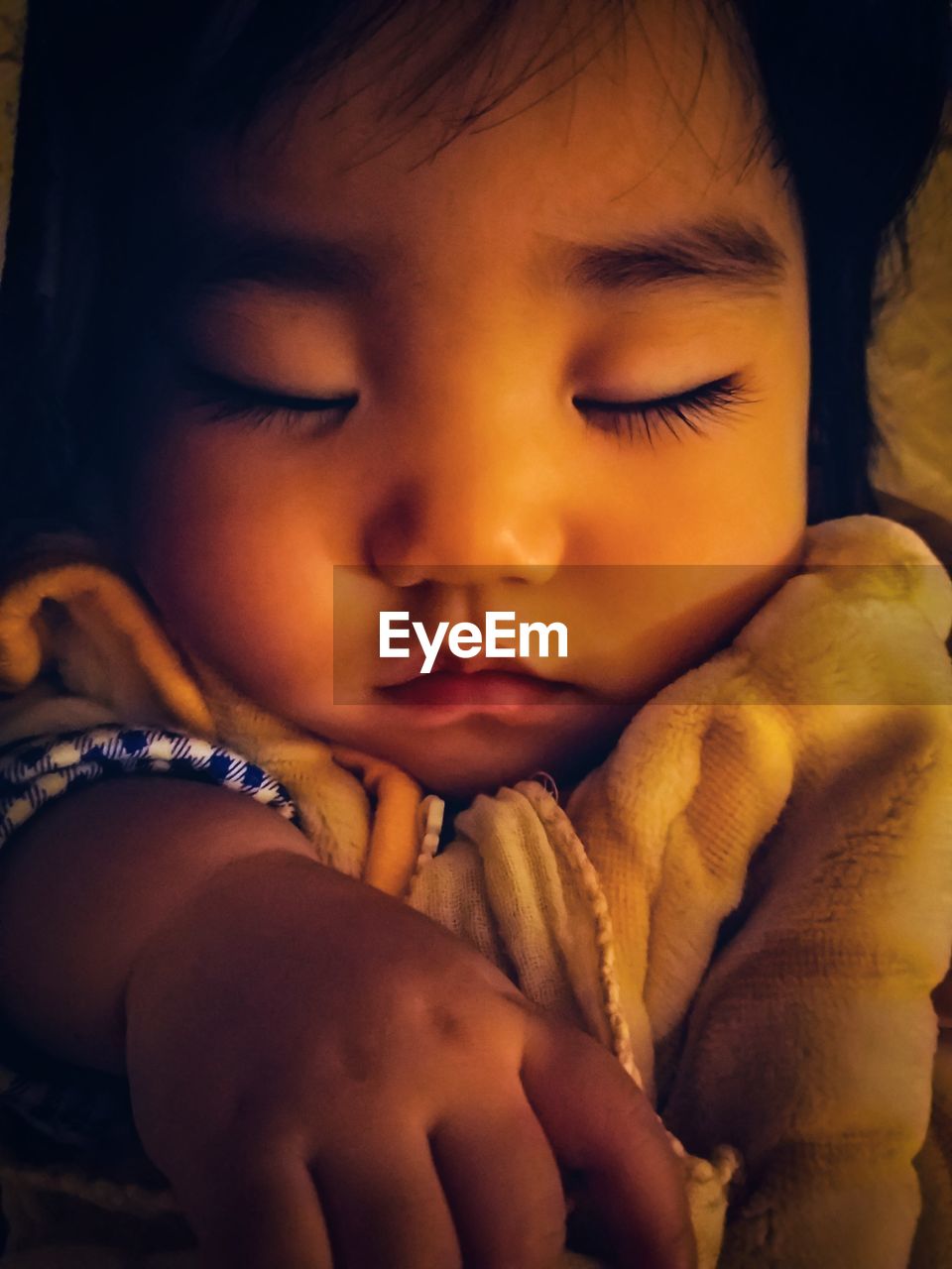 Close-up of cute baby girl sleeping on bed at home