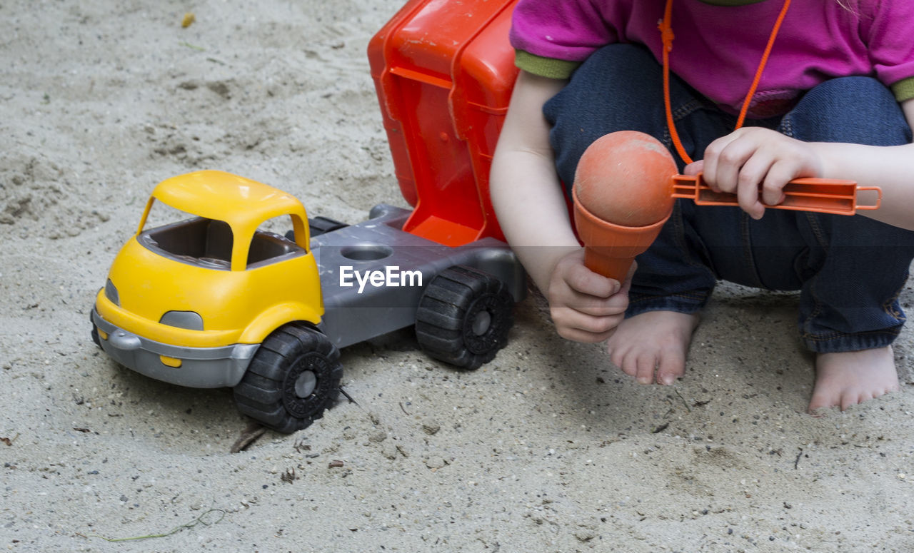 Low section of boy playing with toy car at beach