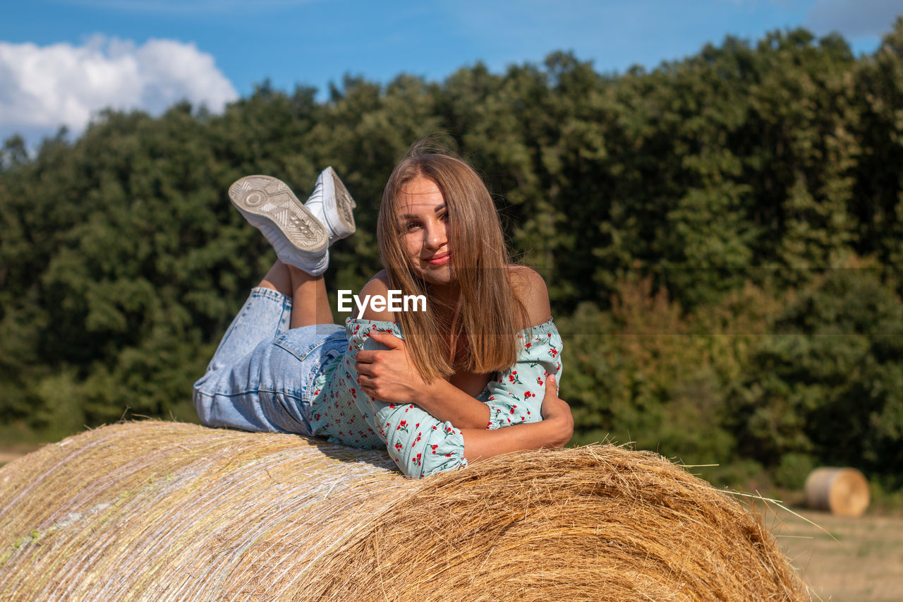 A beautiful young girl is lying on a hay bale