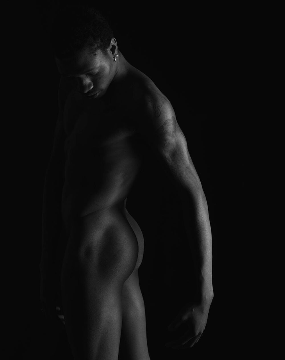 Naked man against black background