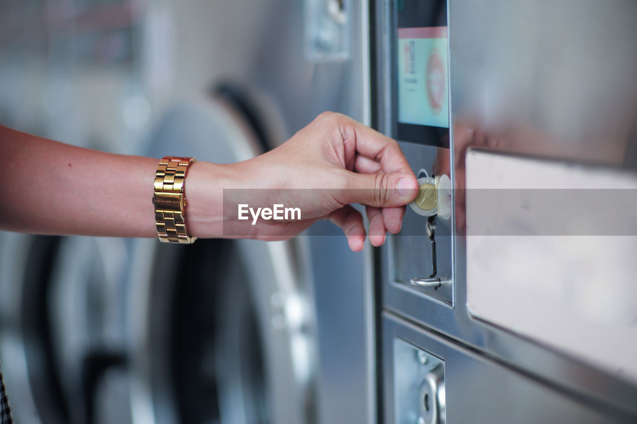 Cropped hand of woman inserts the coin into the vending machine