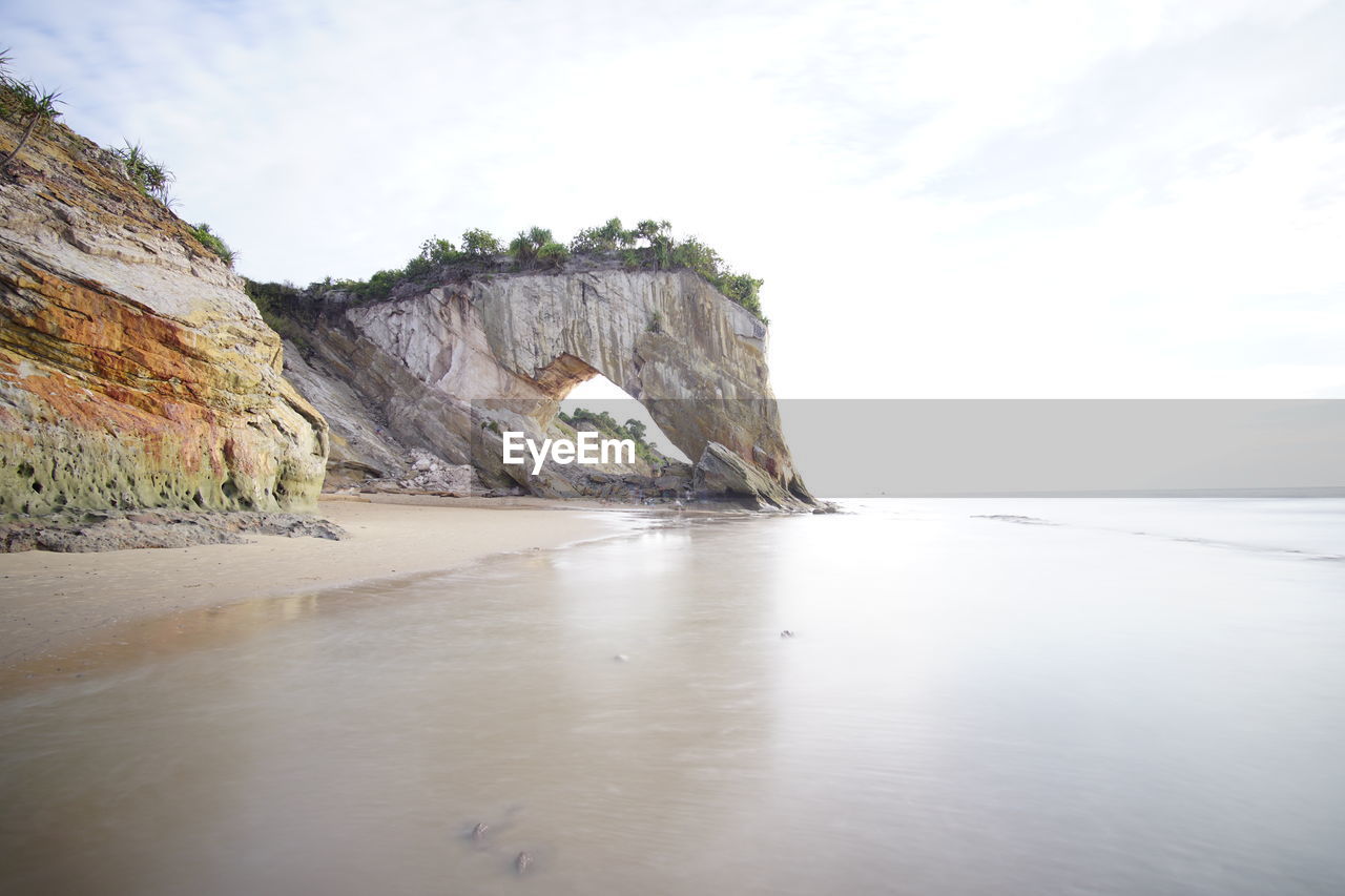 ROCK FORMATIONS ON SEA SHORE AGAINST SKY