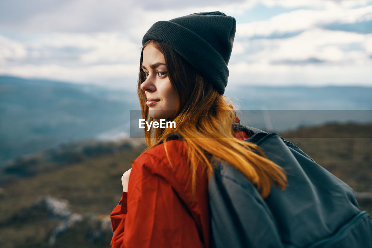 YOUNG WOMAN LOOKING AT CAMERA AGAINST SKY