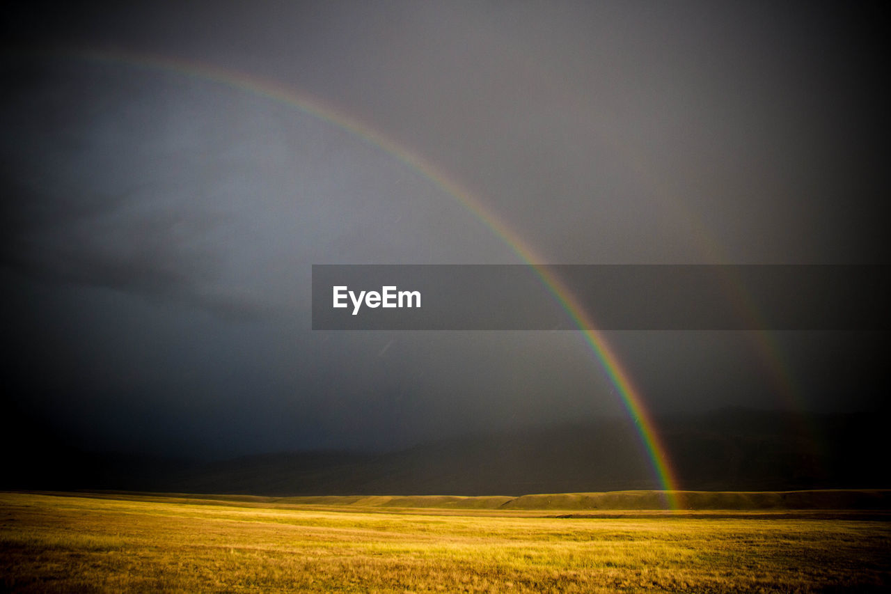 RAINBOW OVER FIELD AGAINST SKY