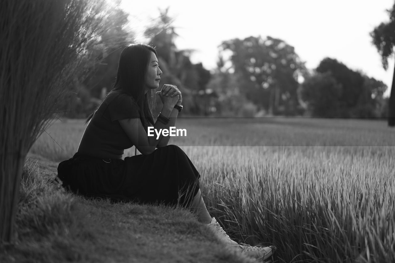 Side view of woman sitting on field