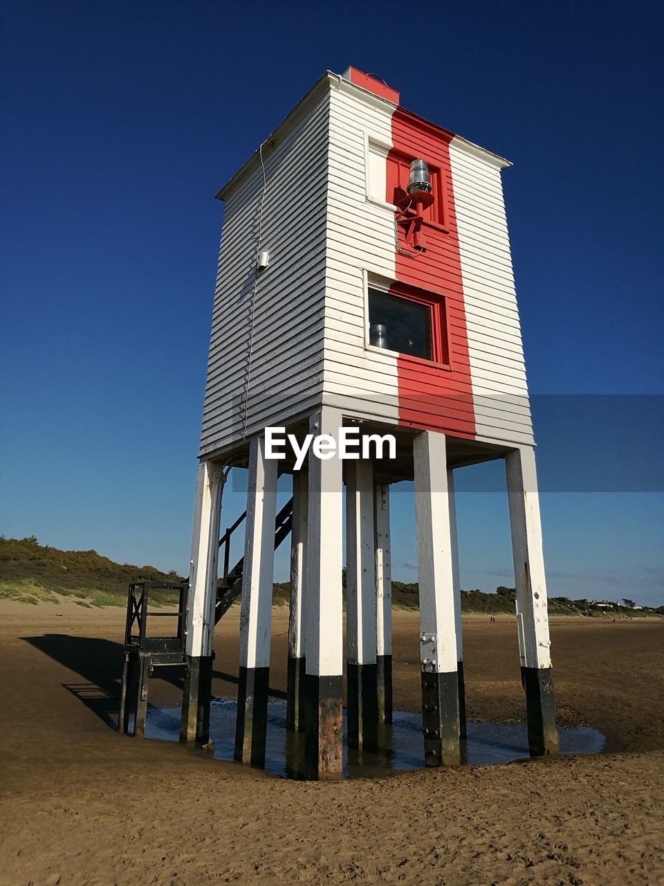 LOW ANGLE VIEW OF TOWER ON BEACH AGAINST BLUE SKY