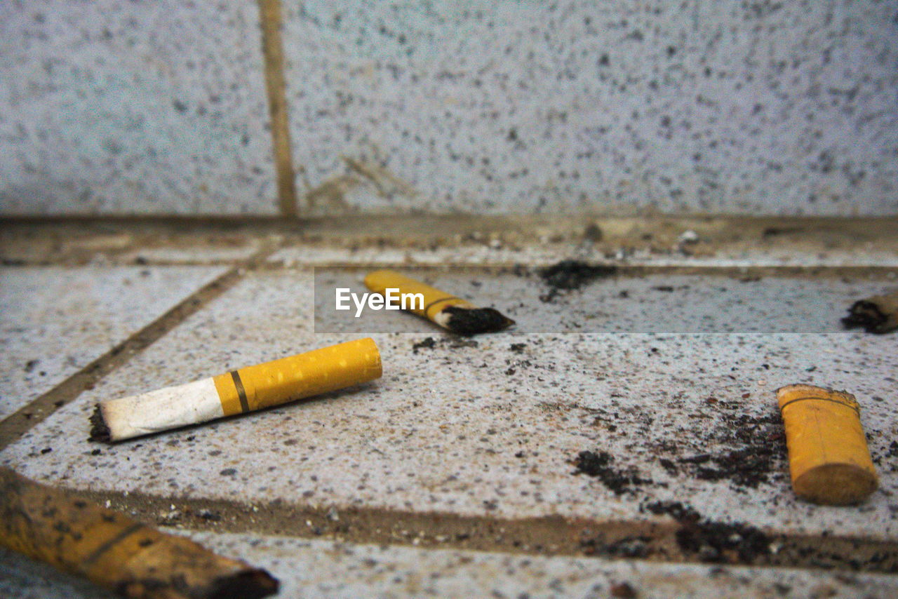 Close-up of cigarette butts on footpath