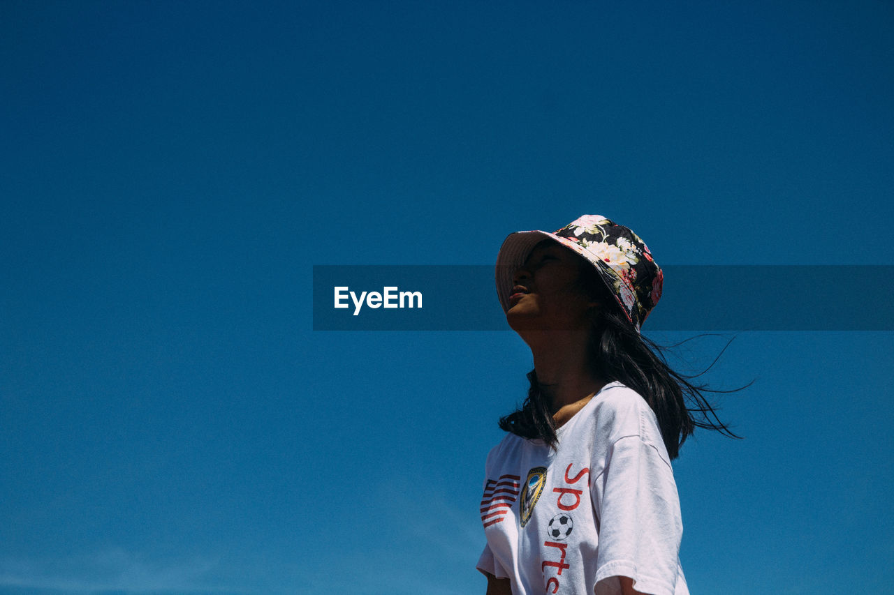 Low angle view of woman against blue sky