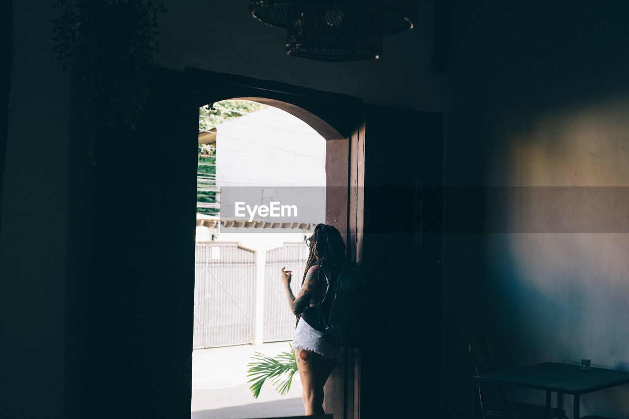 WOMAN STANDING AGAINST WINDOW IN BUILDING